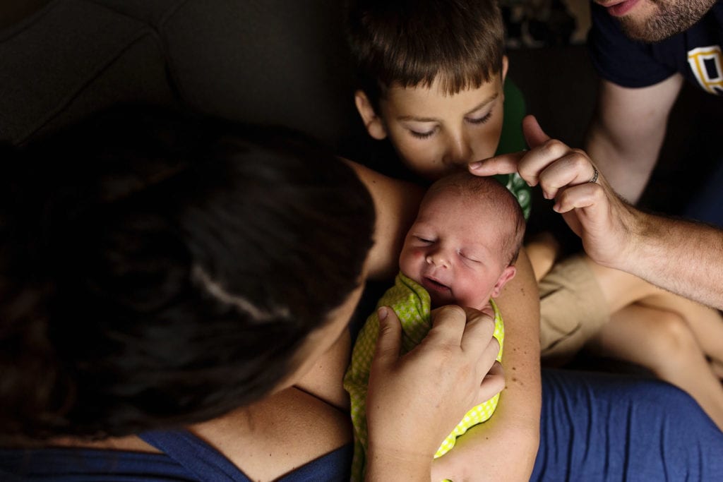 family looking at newborn and stroking his head during Modern Cornwall family photography session