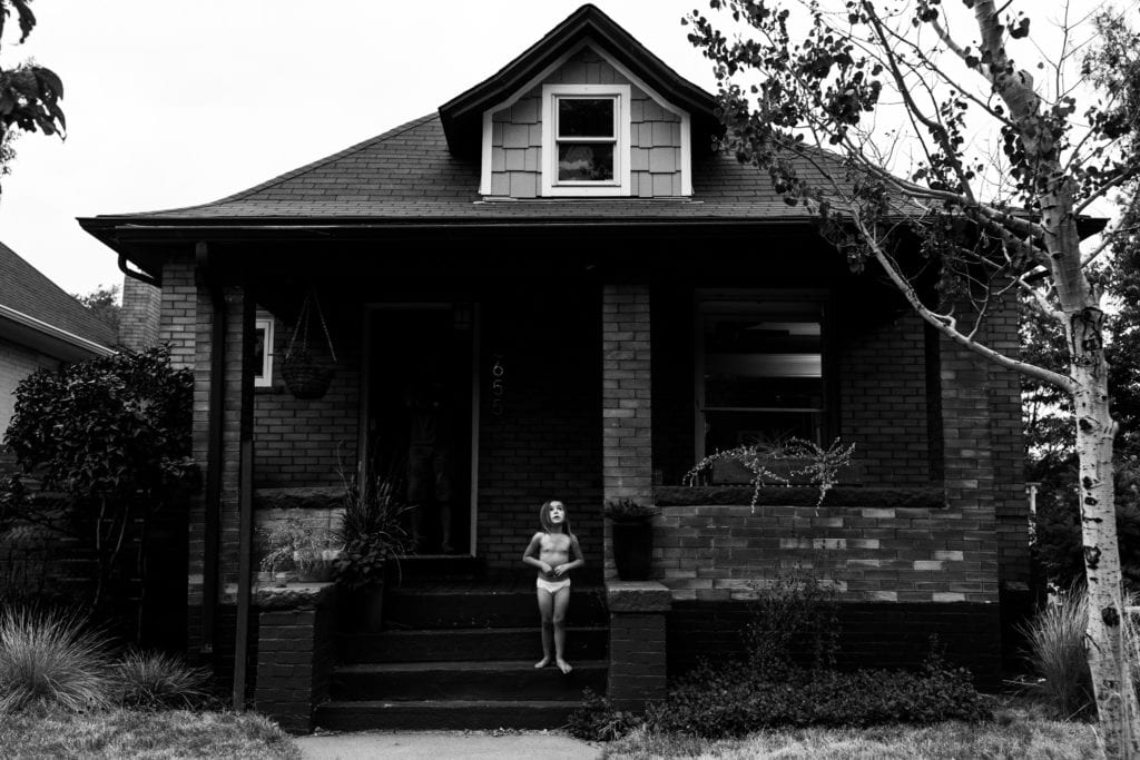 girl looking up at sky in front of house in her underwear during Modern Cornwall family photography session