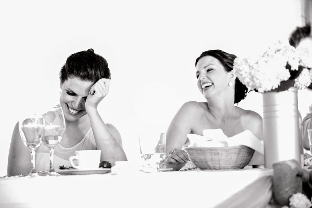 two women laughing while one holds head in hands during Cornwall wedding