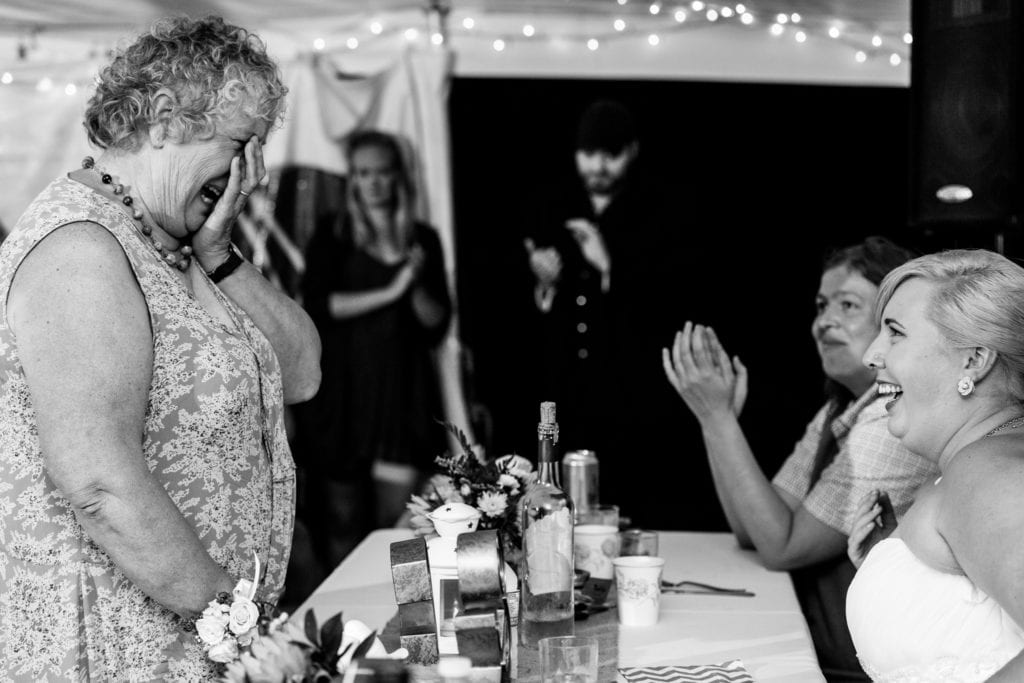 woman holding face and crying in front of brides at Cornwall wedding