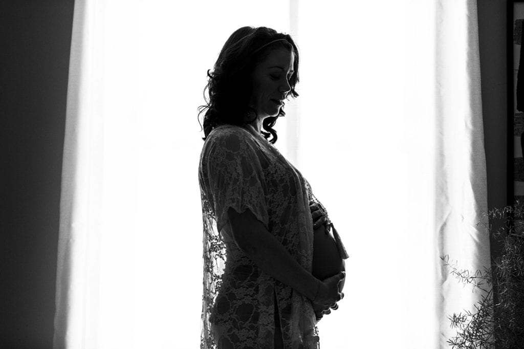 pregnant woman in lace in silhouette in front of window