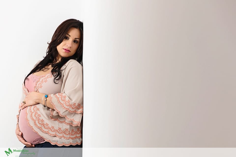 Maternity photography in Cornwall - woman leaning on wall in pink camisole