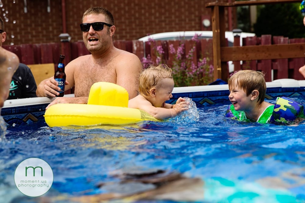 little boy splashing brother in pool