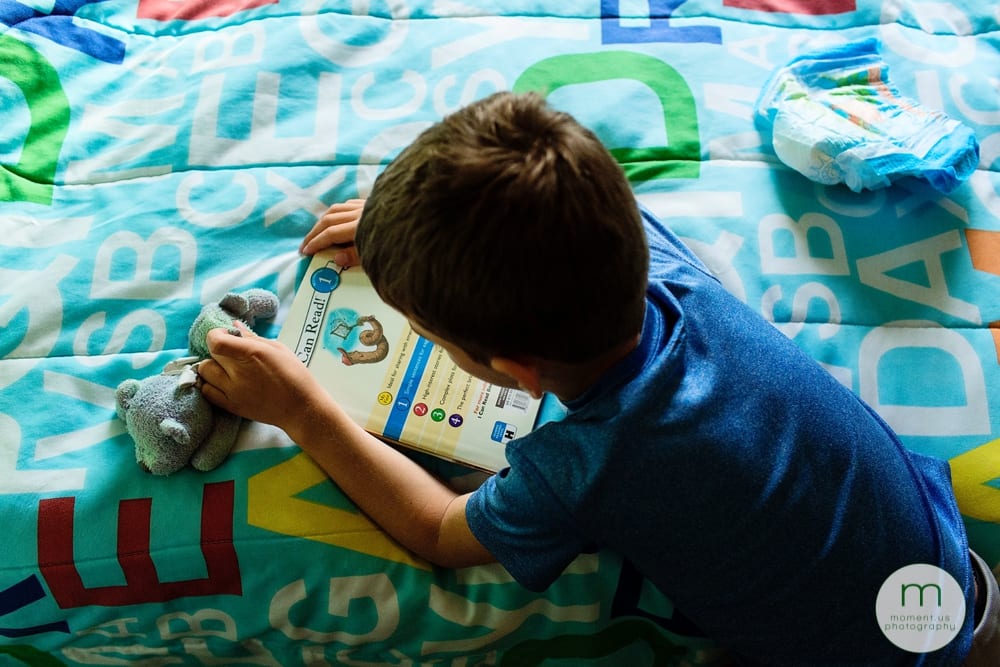 boy on bed with book and pull up