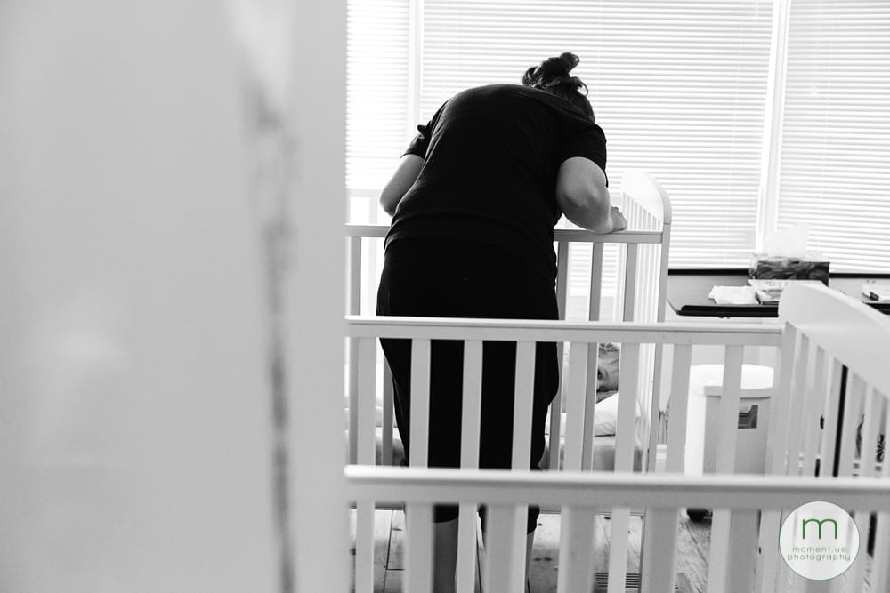 mom looking at girl in crib