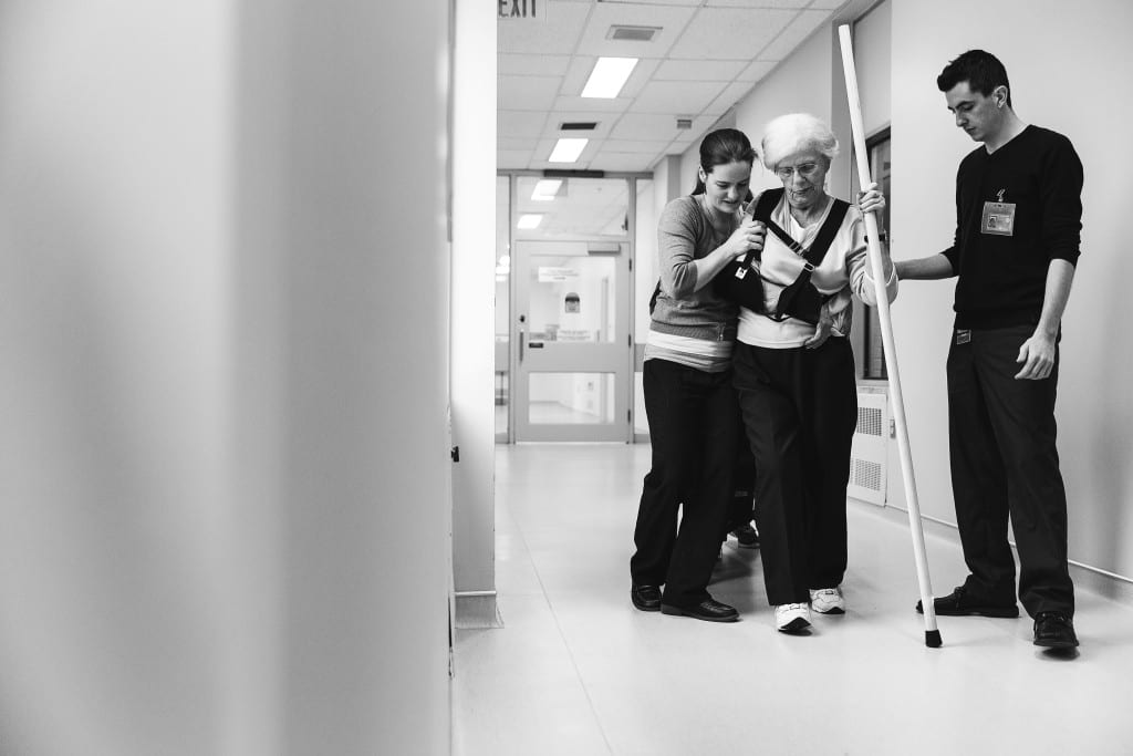 therapist helping patient walk with pole