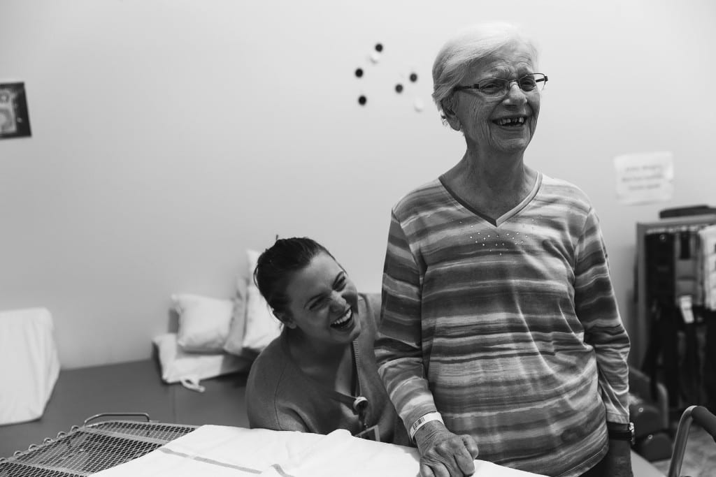 therapist sitting while patient stands and laughs