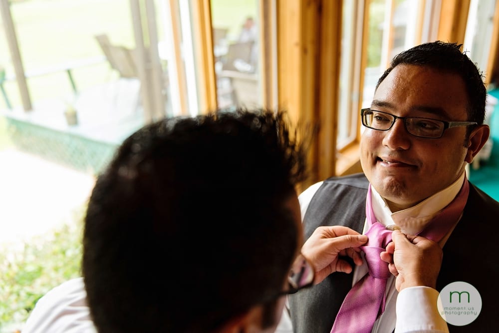 groom making face while tying tie