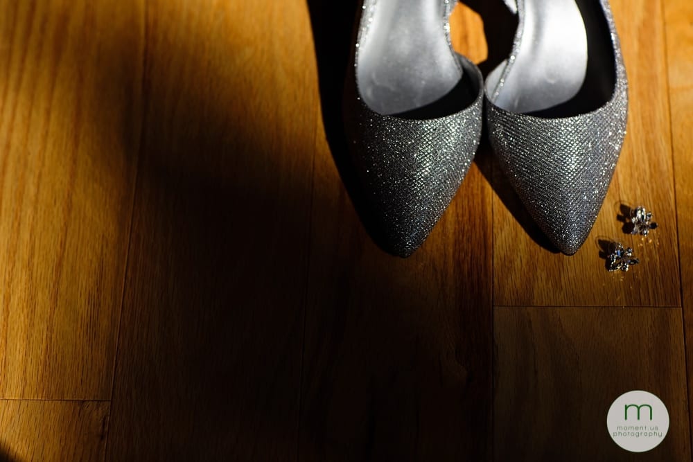 bride's shoes and earrings on hardwood floor