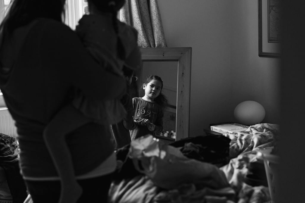 London girl playing on bed while mom watches