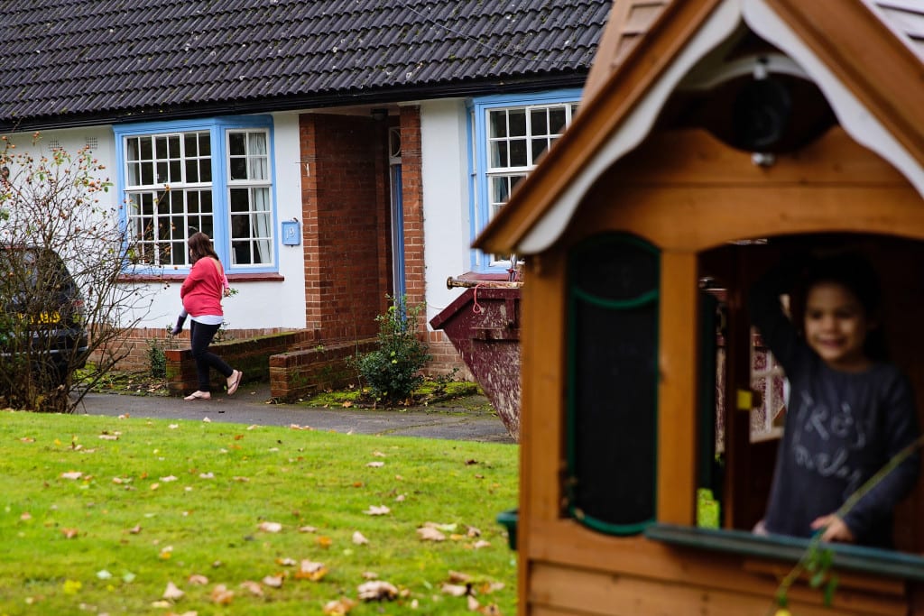 girl in playhouse while mom loads the car