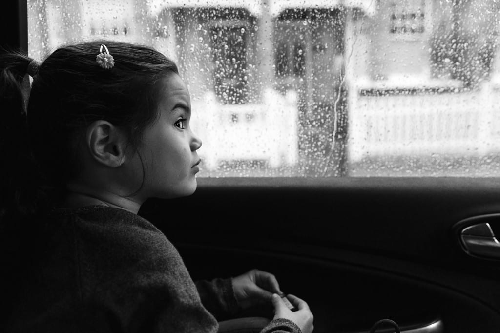 London girl looking out window at rain