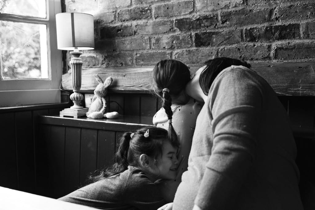 London family cuddling on pub bench