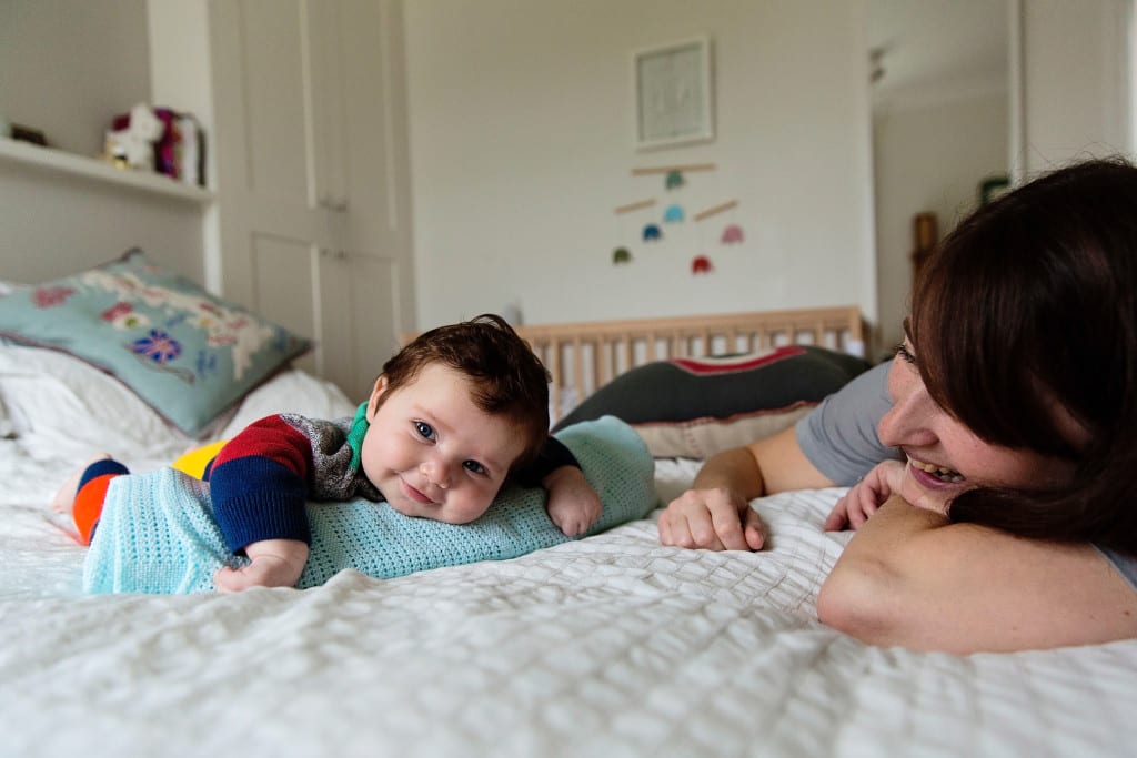 London baby having tummy time with big smile