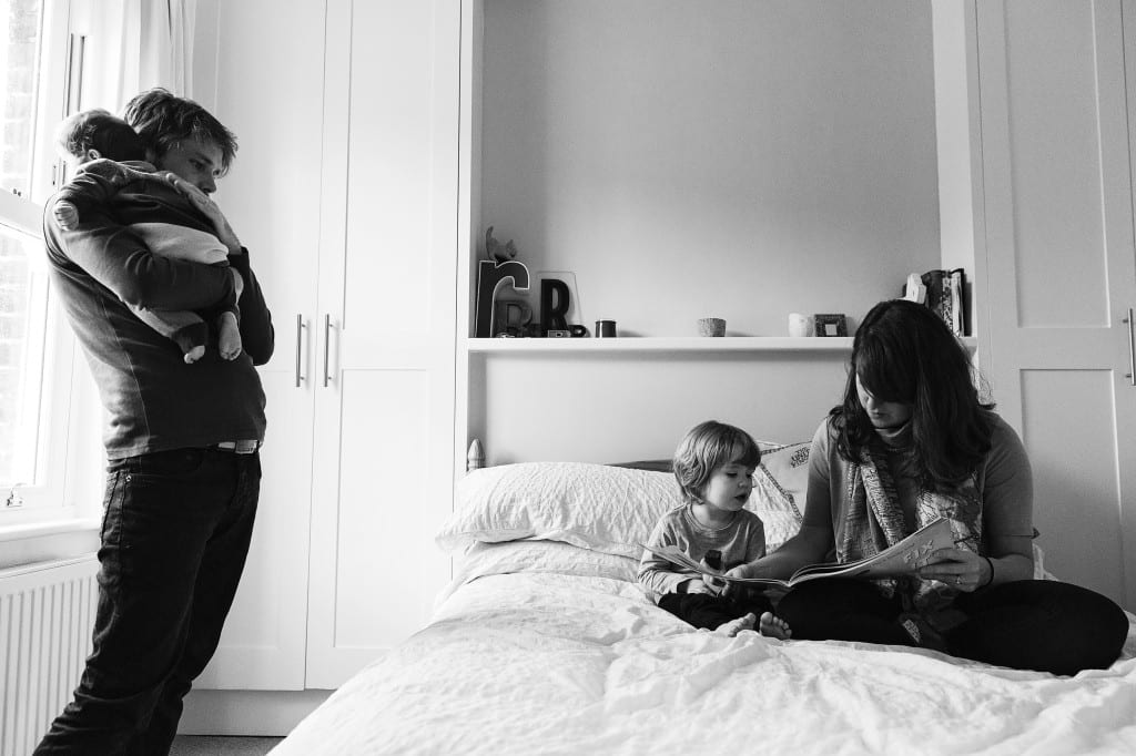 London family reading book with dad by window