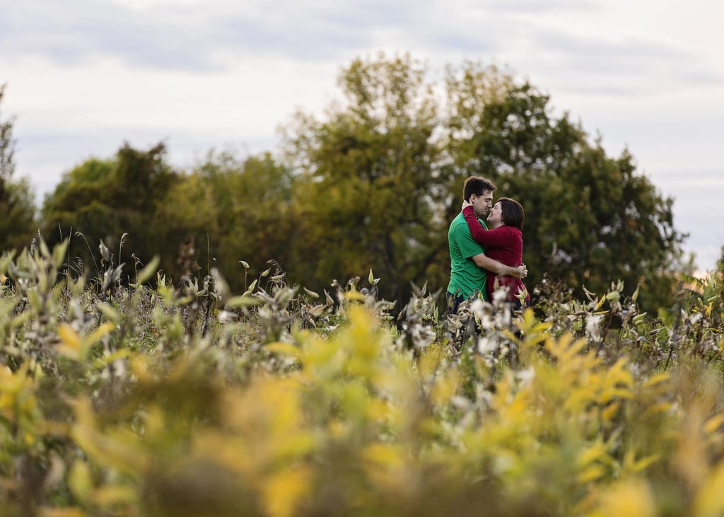 Ontario wedding photographer - couple cuddling for Cornwall engagement photos in abandoned field