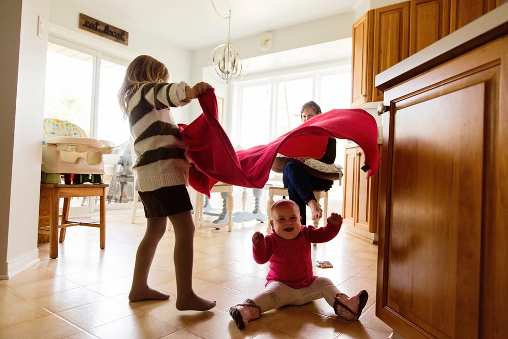 Cornwall family photographer - sisters playing with blanket in kitchen
