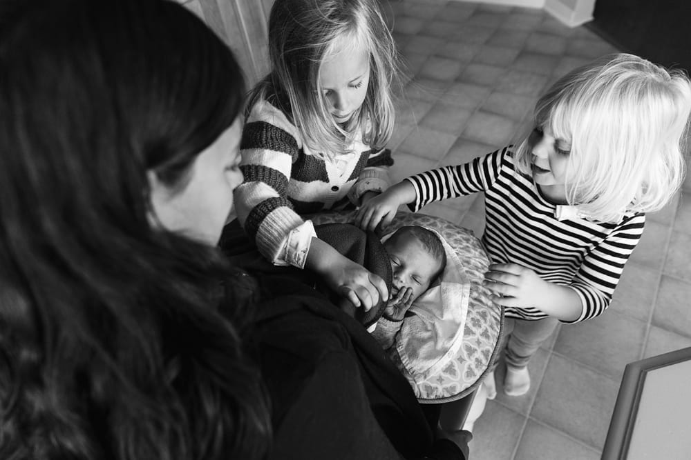 Cornwall family photographer - sisters helping with newborn