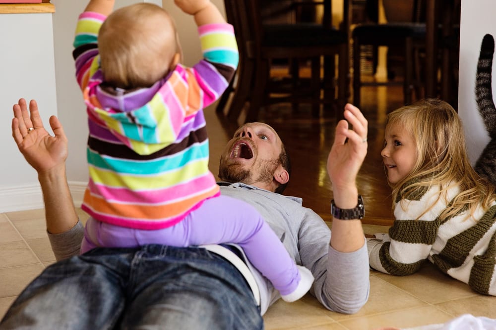 Cornwall family photographer - dad with sisters in kitchen