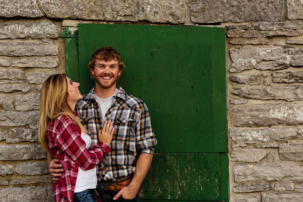 Ontario wedding photographer - couple cuddling for Cornwall engagement photos in front of green door