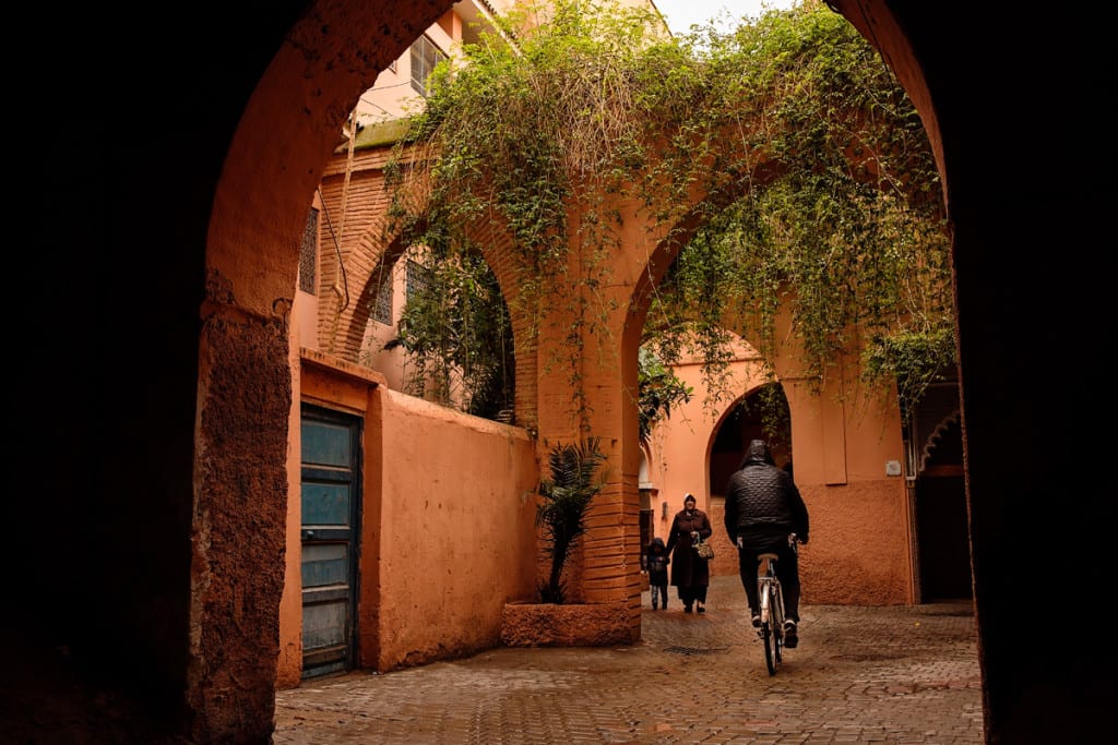 Wedding photographer in Morocco - cyclist and woman with child under archway