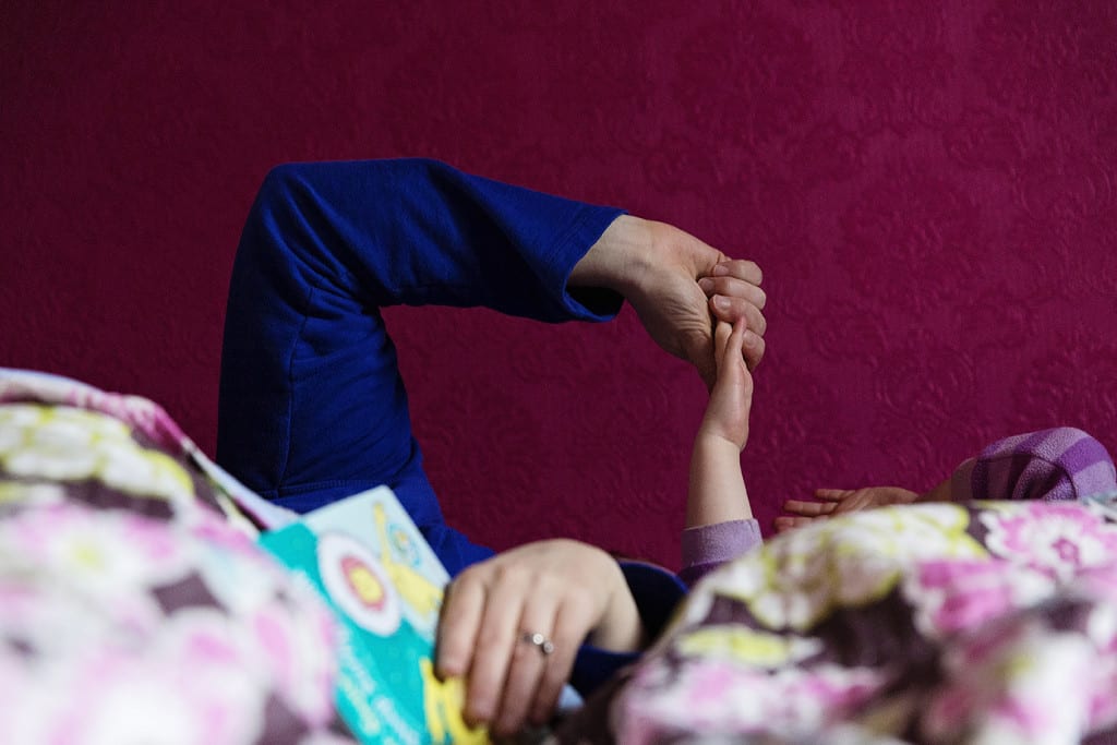mom holding daughter's hand in bed