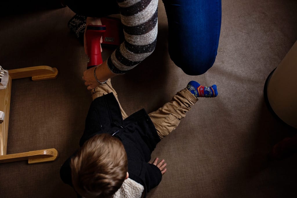 mom putting son's rubber boots on
