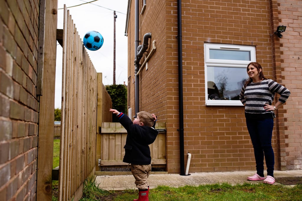 boy throwing ball over wall during South Wales family session