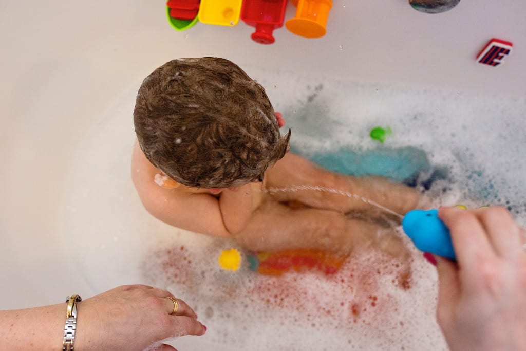 boy being squirted by bath toys during South Wales family session