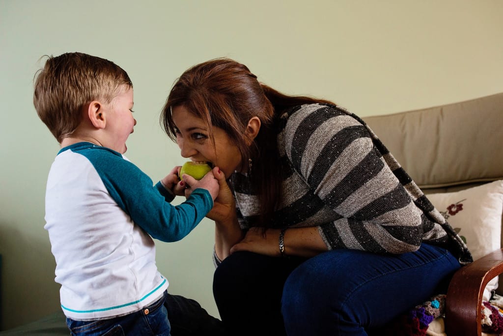 mom taking bite of son's apple during South Wales family photo session