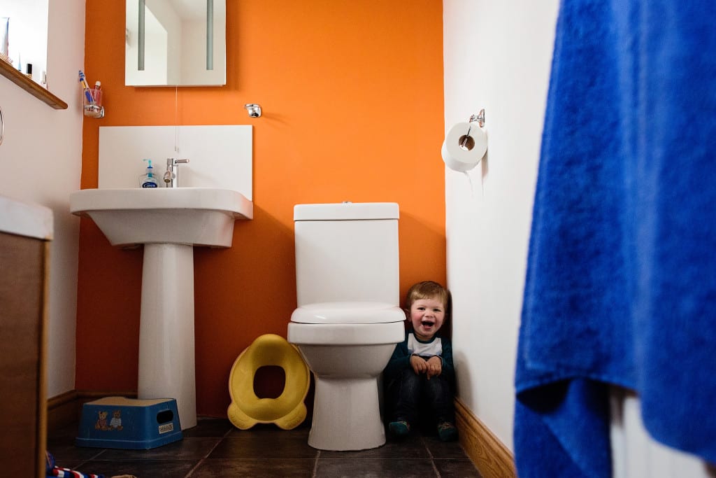 boy hiding next to toilet during session with South Wales family photographer
