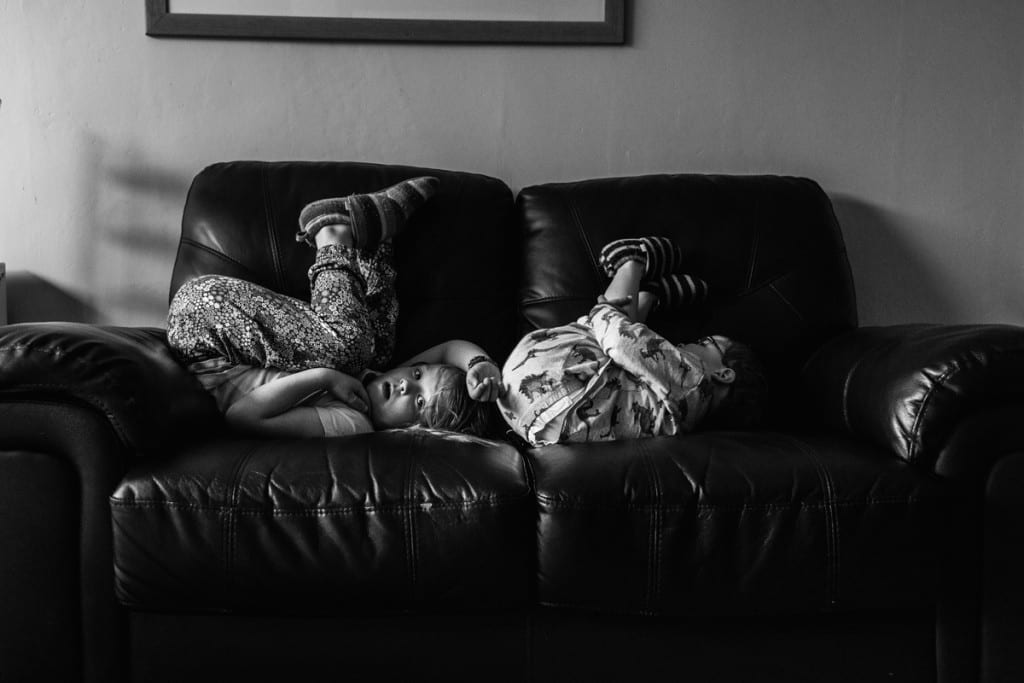 brother and sister playing on couch during London family photography session