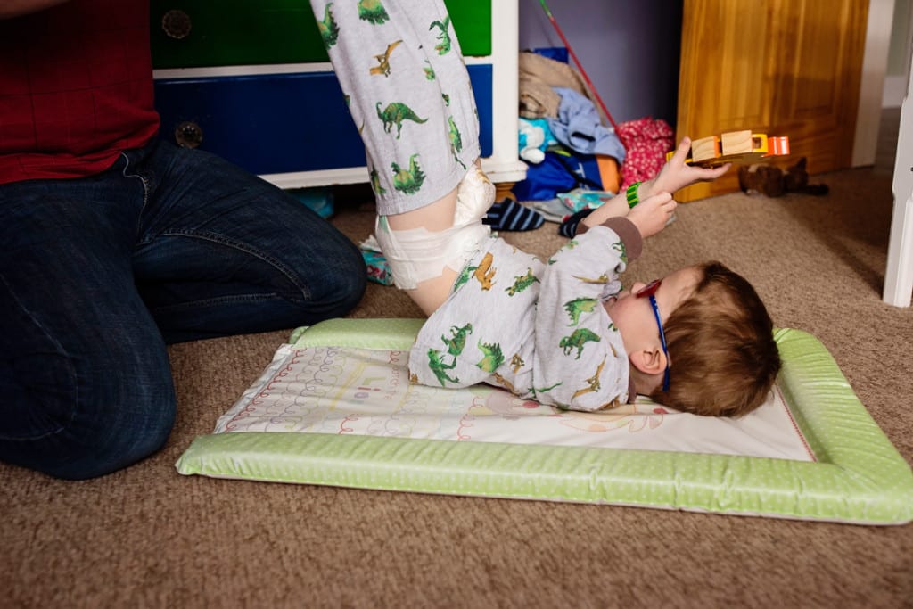 son playing with toy while getting diaper changed during London family photography session