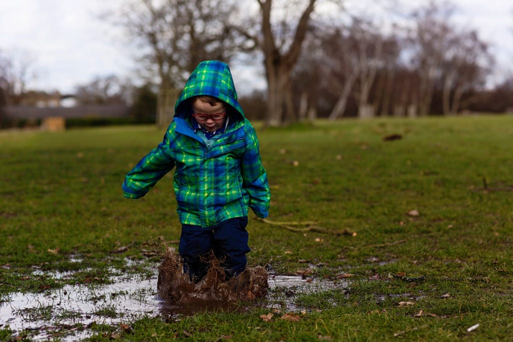 boy splashing in puddle during London family photography session