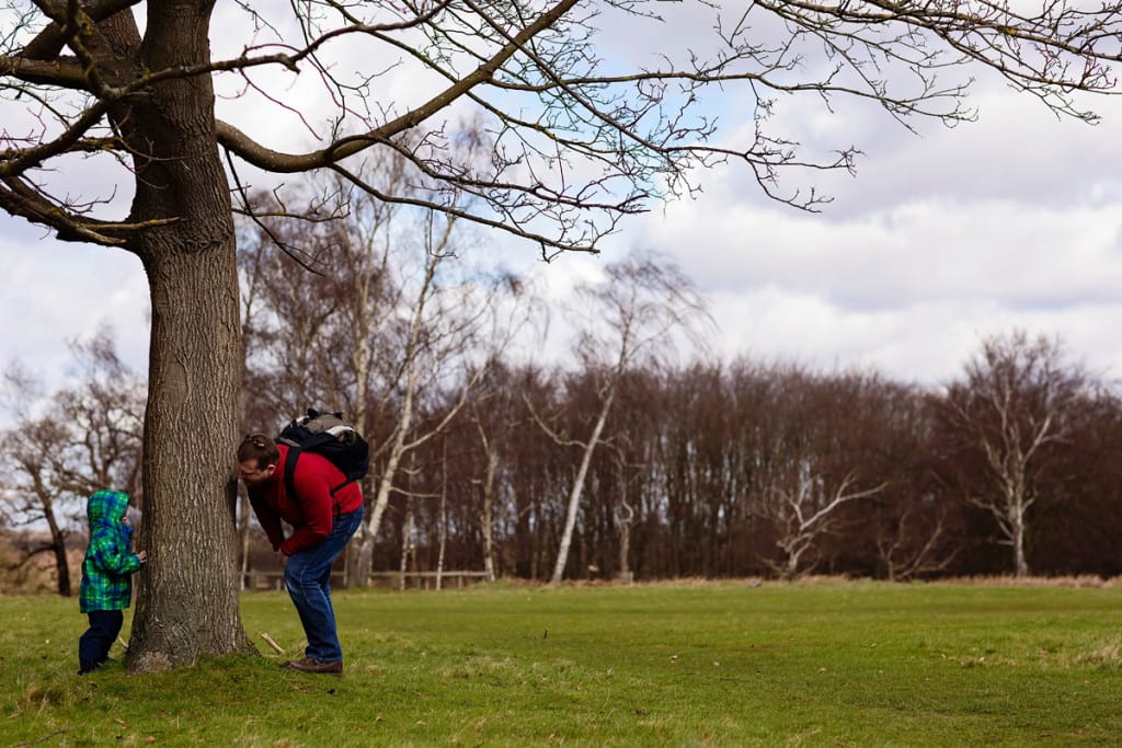 Father and son playing by tree during London family photography session