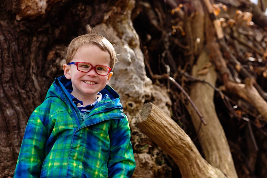 Boy smiling on tree during London family photography session