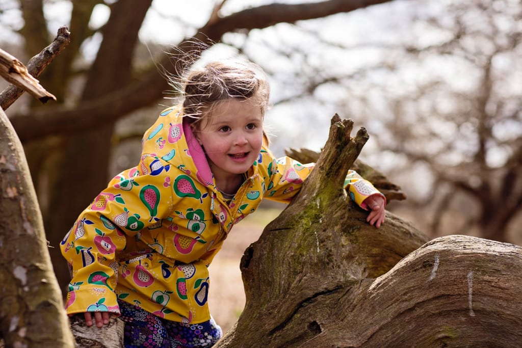 Girl playing on tree trunk during London family photography session
