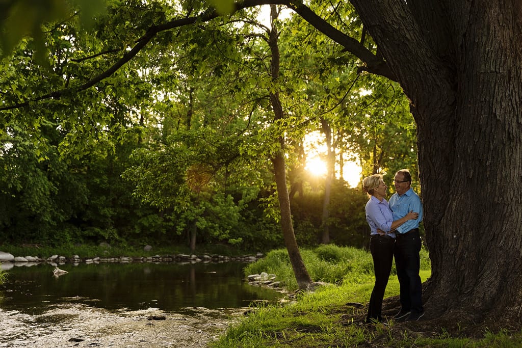 Couple standing under tree next to river