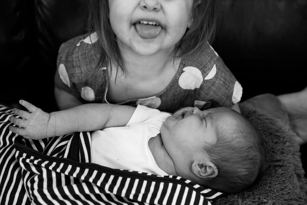 sister excited about holding brother during family portrait session