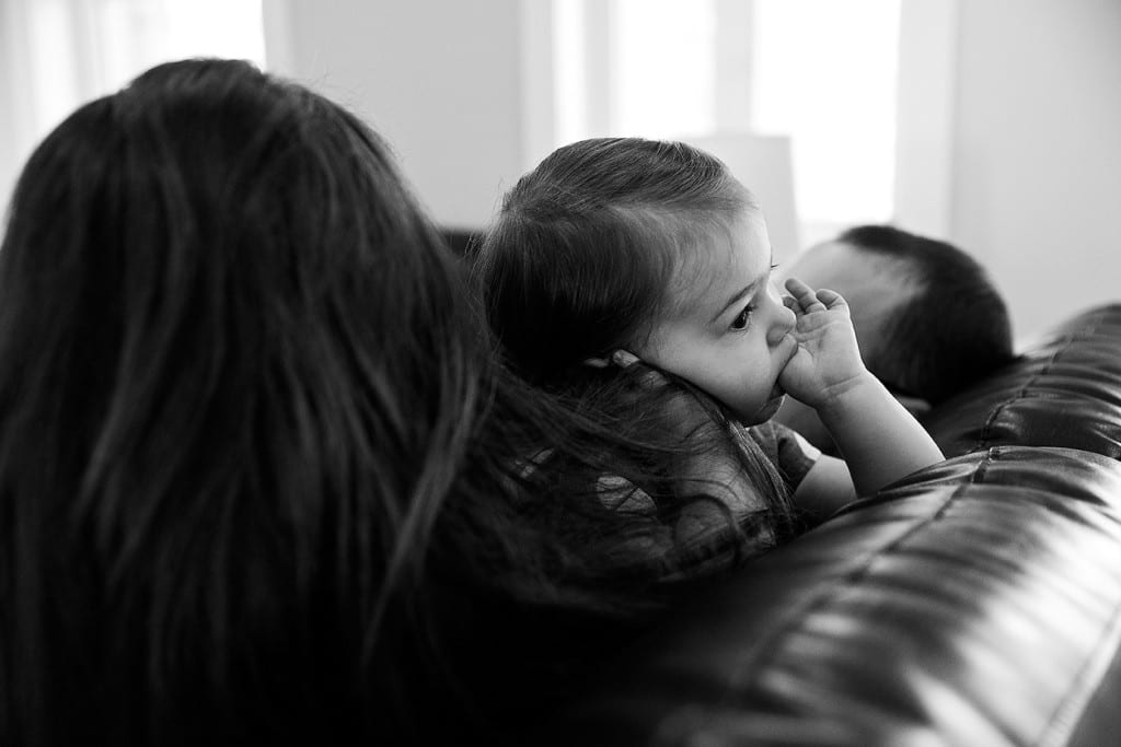 girl holding mom's hair and sucking thumb during family portrait session