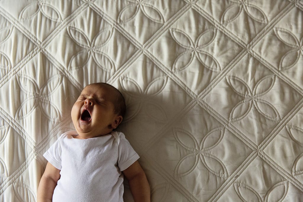 baby yawning on bed during candid Cornwall family portraits