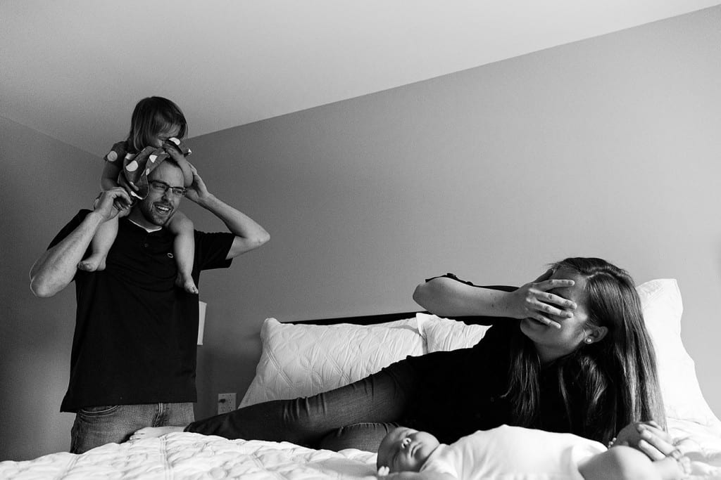 mom laughing at daughter on dad's head during candid Cornwall family portraits session