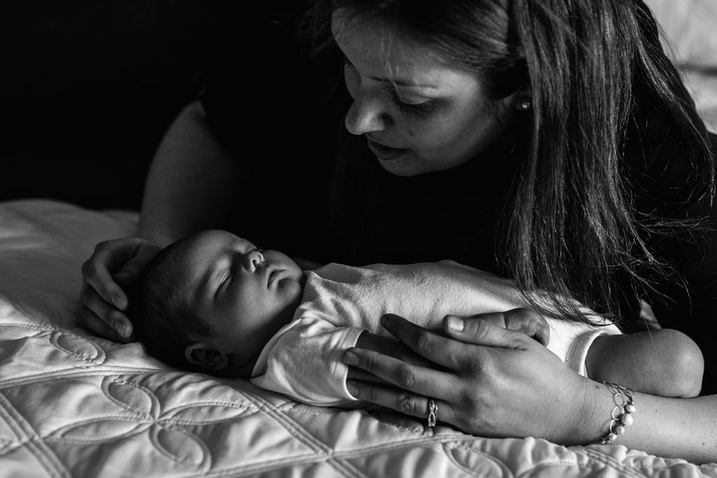 mom on bed looking at baby during family portrait session