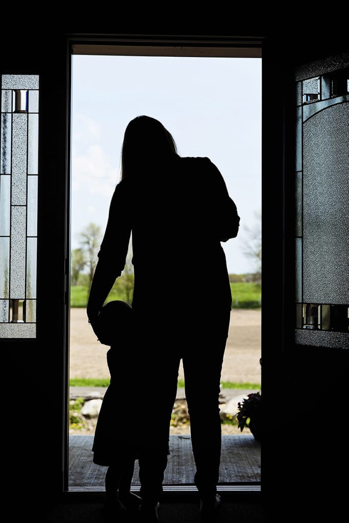 mom holding baby and daughter in doorway during family portrait session