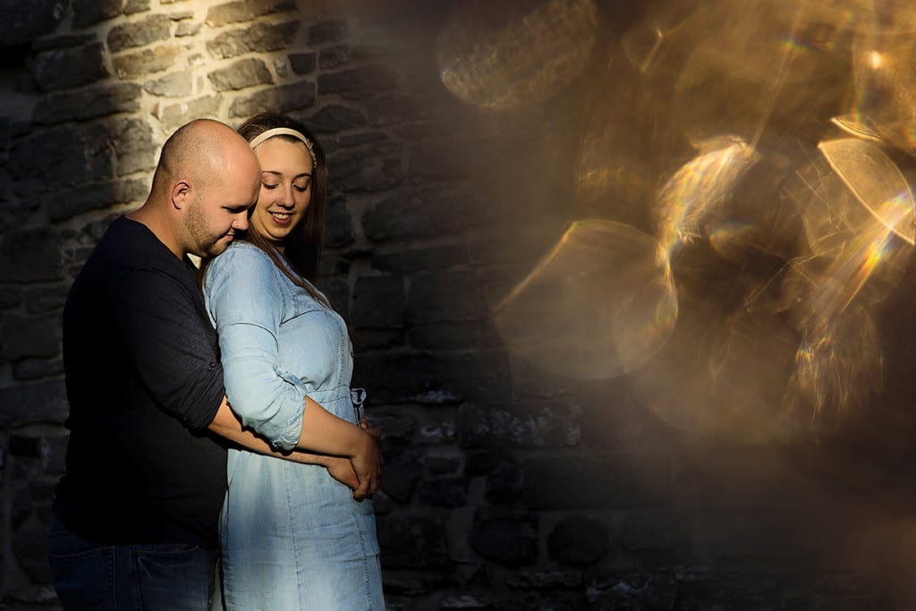 Couple cuddling in spotlight with wine glass bokeh during St Raphael's engagement session