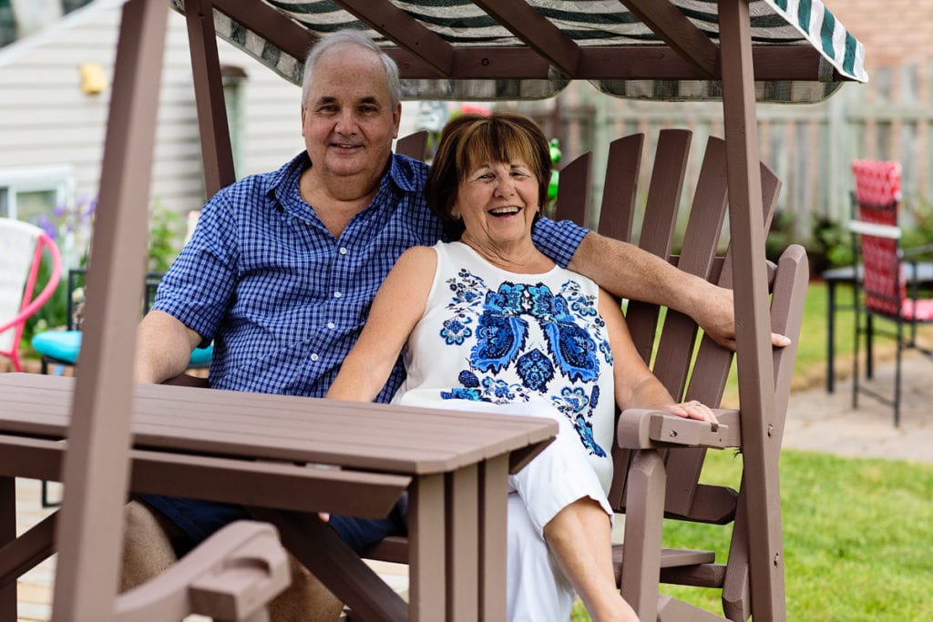 couple laughing on back yard swing during candid cornwall family photography session