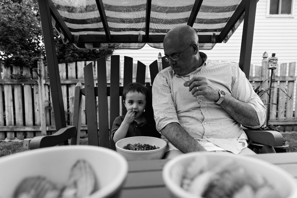 little boy and dad eating snacks on swing