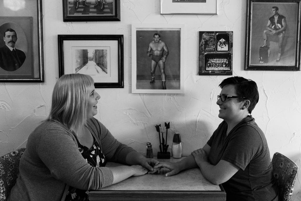 Women holding hands across diner table