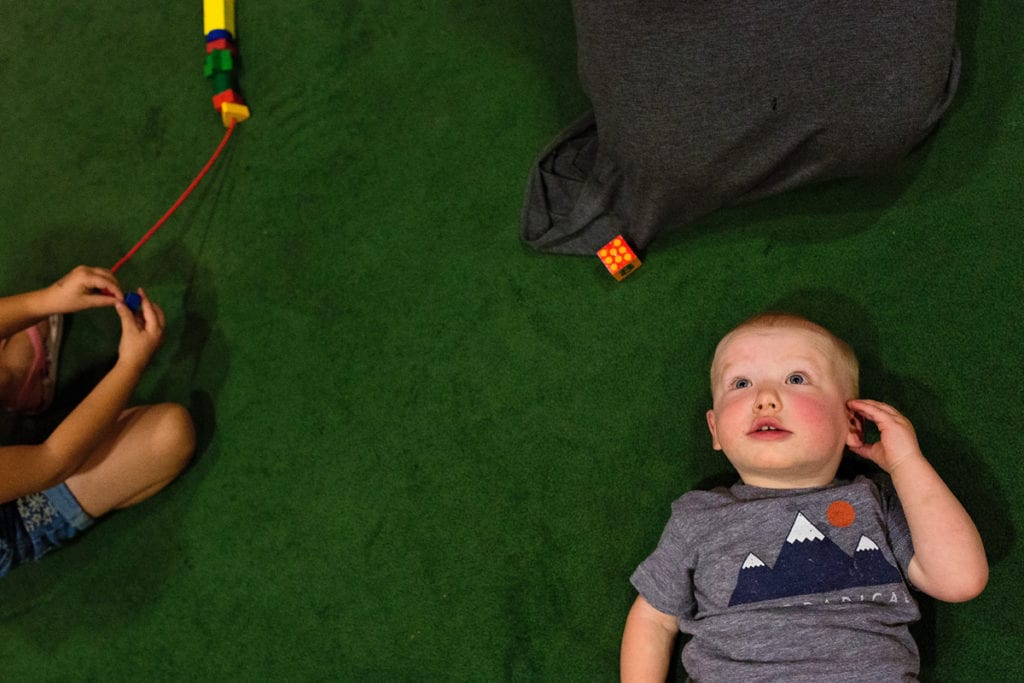 Baby staring at ceiling on green carpet