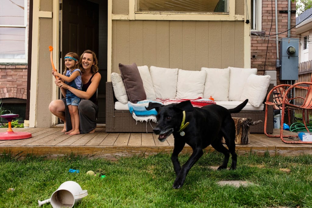 Mom and daughter in yard with black dog